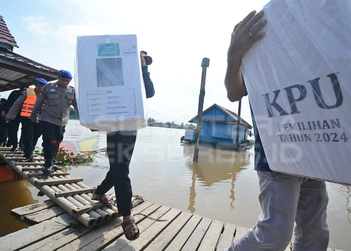 KAWAL DISTRIBUSI-Petugas KPPS membawa logistik menuju TPS 26 di Pulau Seribu Kelurahan Ogan Baru Kecamatan Kertapati dengan pengawalan petugas gabungan. Foto: Alfery Ibrohim/Sumateraekspres.id