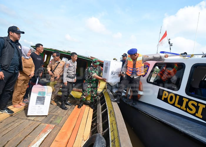 SERAH TERIMA-Petugas pengawalan distribusi melakukan serah terima logistik pemilu kepada pihak KPPS di atas kapal jukung milik seorang warga di TPS 24 Kelurahan Ogan Baru Kecamatan Kertapati. Foto: Alfery Ibrohim/Sumateraekspres.id