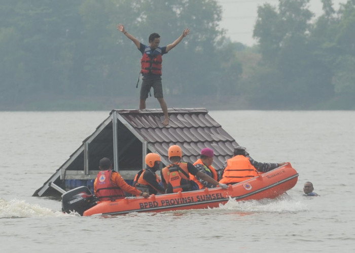 Selamatkan Korban Banjir - Petugas dari Badan Penanggulangan Bencana Daerah (BPBD) Sumsel  dan Tim Gabungan melakukan penyelamatan korban banjir bandang yang berada diatas atap rumah dengan menggunakan perahu karet. Kegiatan ini merupakan simulasi penanganan banjir di Venue   Dayung Jakabaring Palembang. Rabu, (23/10/2024).  Foto:Budimaan/Sumateraekspres.id