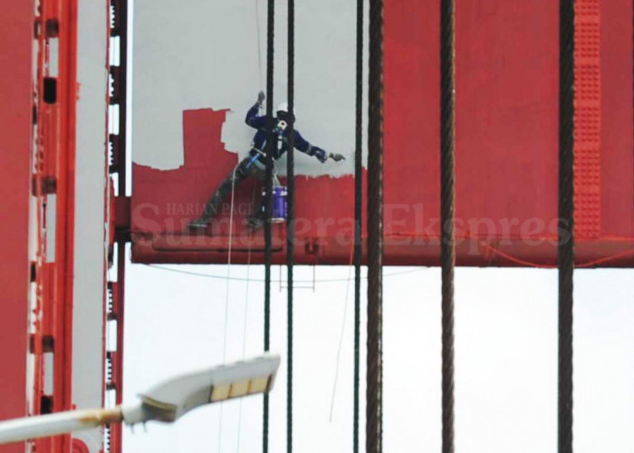 BERIKAN HASIL MAKSIMAL-Pekerja melakukan pengecatan salah satu menara Jembatan Ampera Palembang yang memiliki ketinggian 63 Meter dengan menggunakan APD lengkap, full body harness, serta memiliki sertifikat khusus dan telah dilindungi oleh BPJS Ketenagakerjaan, Sabtu (22/07/2023). Pekerja tersebut dapat bekerja dengan tenang, memberikan hasil maksimal dan terbaik karena dalam bekerja telah memenuhi standar keselamatan K3.  Foto : Budiman/Sumateraekspres.id