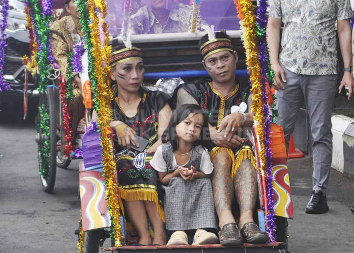 PAKAIAN ADAT DAYAK-Salah satu pasangan pengantin nikah massal Pemkot Palembang menggunakan pakaian daerah Kalimantan Timur berupa Baju Dayak pada arak-arakan dari Kantor Wali Kota Palembang menuju Rumah Dinas Wali Kota Palembang.  Kamis,  (30/11/2023). Foto : Budiman/Sumateraekspres.id