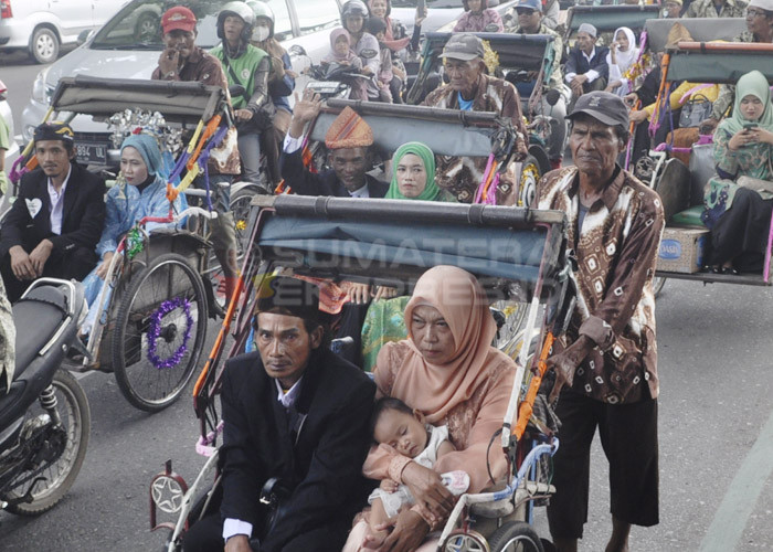 BAWA BALITA-Salah satu pasangan nikah massal membawa anak yang masih balita ketika mengikuti arak-arakan menggunakan becak dari kantor Wali Kota Palembang ke rumah dinas Wali Kota Palembang.  Kamis,  (30/11/2023).  Kegiatan Nikah massal ini diikuti ratusan pasangan dan diselenggarakan oleh Pemkot Palembang. Foto : Budiman/Sumateraekspres.id