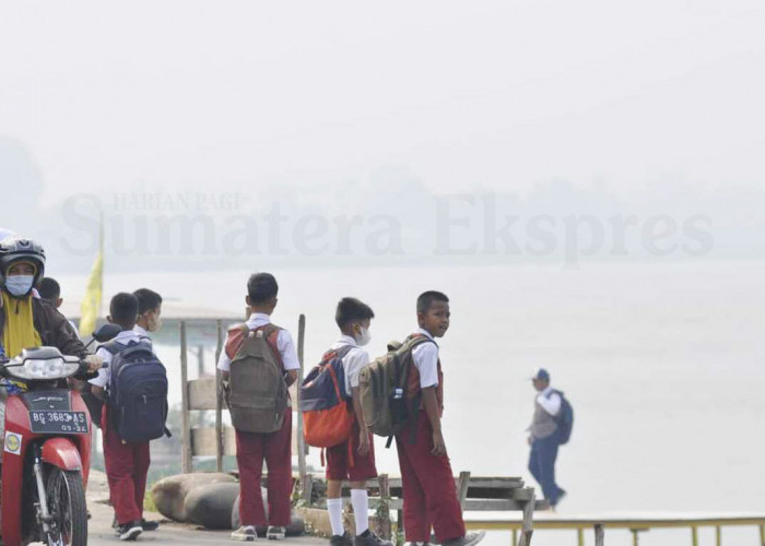 MENUNGGU PERAHU-Siswa dari SDN 84 Palembang menunggu jemputan perahu getek untuk menuju sekolah dengan menyusuri Sungai ogan, walaupun kabut asap masih melanda kota Palembang. Pemerintah kota Palembang kembali memberlakukan pembelajaran tatap muka setelah sebelumnya mengeluarkan edaran belajar daring dari tanggal 2-16 Oktober kemarin, Selasa (17/10/2023). Foto : Budiman/Sumateraekspres.id